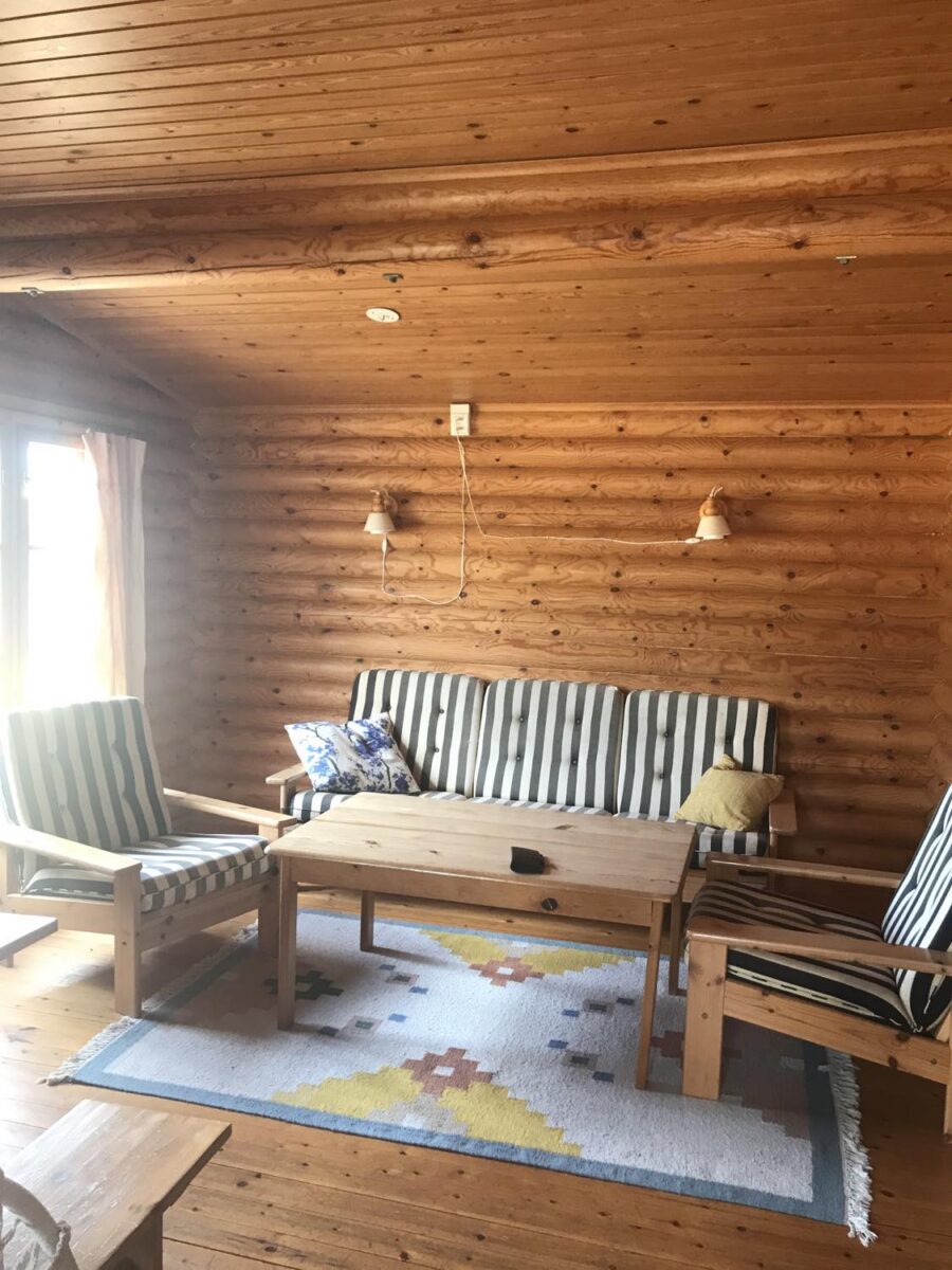 allrum med randig soffa från 70 talet alla väggar o tak i stugan är omålade, furu
